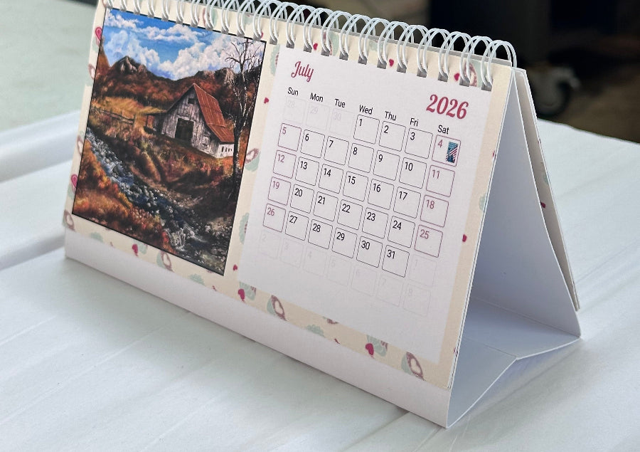 2026 faith-inspired desk calendar open to July, featuring an original forest painting by M. Thompson Art