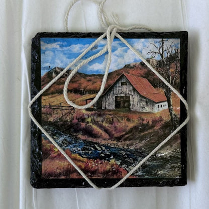 Handcrafted slate coaster featuring countryside barn illustration.