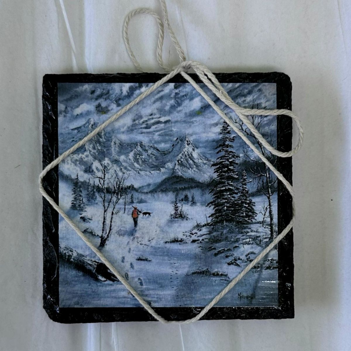 slate coaster small winter landscape painting with mountains and a person on a snowy path, tied with twine.