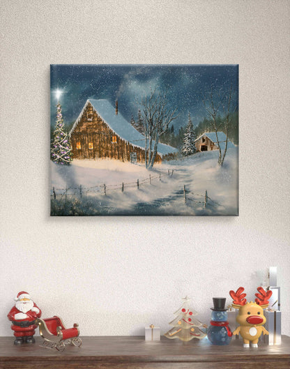 Canvas print of a snowy landscape with a cabin hanging on a wall above a wooden shelf with decorative items.